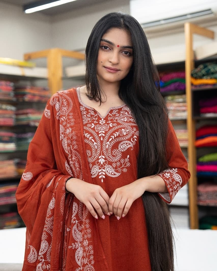 Woman wearing a red traditional outfit with white patterns in a store setting