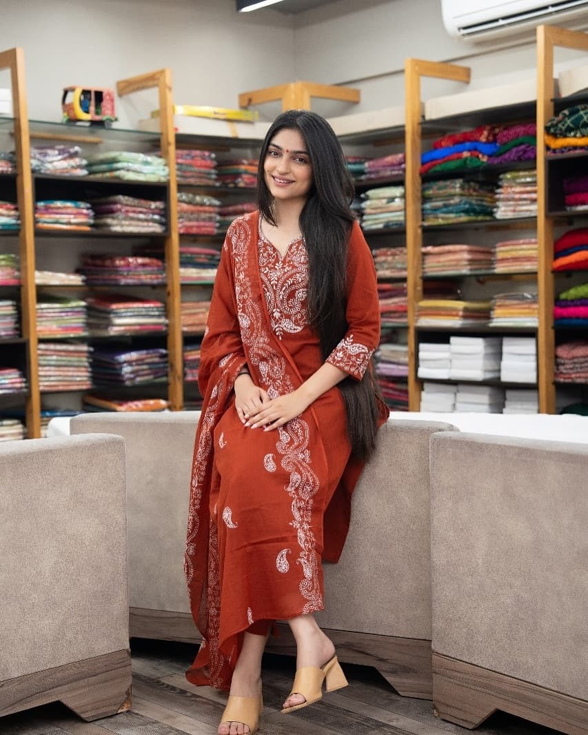 Woman in a red traditional outfit sitting in a fabric store.