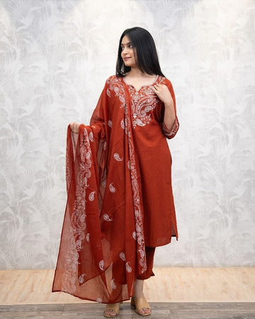 Woman wearing a red traditional outfit with white patterns against a light gray background